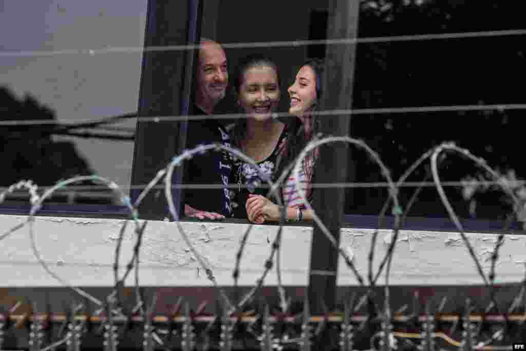 Ivan Simonovis (i) junto a su esposa Bonny (c) y su hija Ivana se asoma por la ventana de su casa.