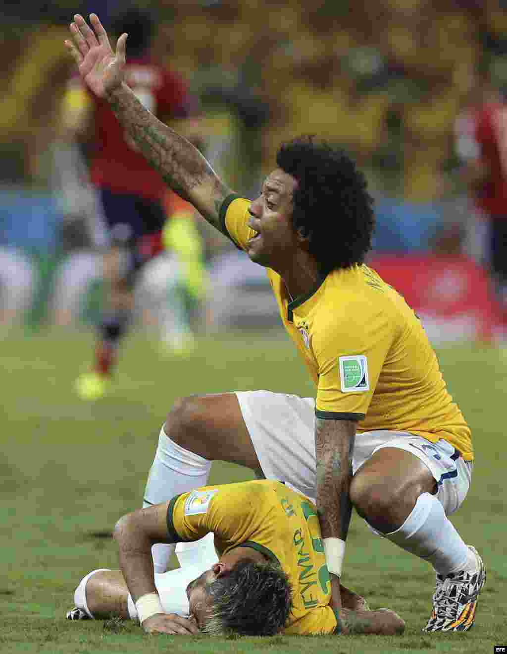El defensa brasileño Marcelo (d) pide la asistencia para su compañero Neymar quien ha recibido un golpe en la espalda, durante el partido Brasil-Colombia, de cuartos de final del Mundial de Fútbol de Brasil 2014, en el Estadio Castelão de Fortaleza, Bras